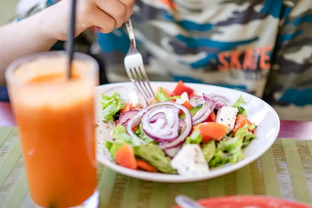 Colorful salad with fresh vegetables and a refreshing drink on a table.